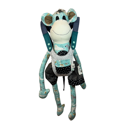 A plush toy baby carrier with a monkey design in teal and chocolate colors, featuring patterned fabric and a safety strap.
